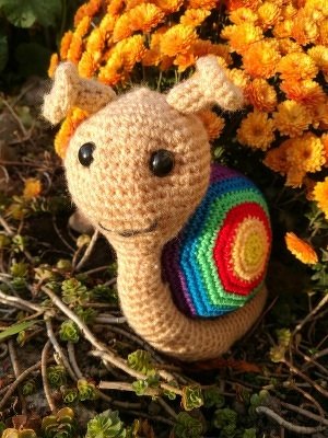 Detailansicht einer gehäkelten Amigurumi-Schnecke mit gestreiftem mehrfarbigem Schneckenhaus