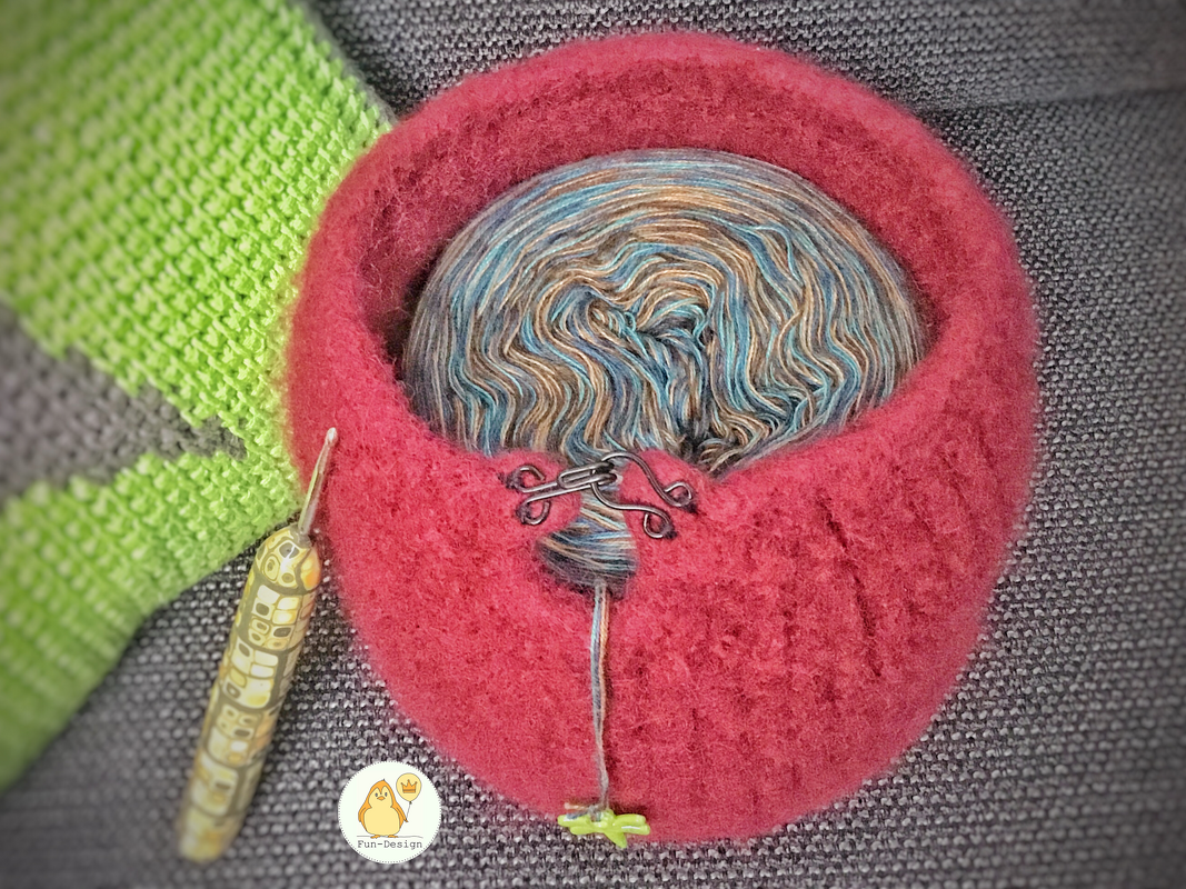 Gefilzte Garnschale mit Garndurchlass, mehrfarbiger Garnkuchen und Häkelnadel