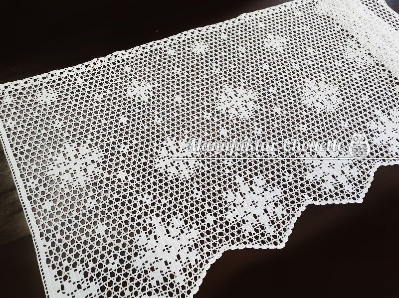 Weiße gehäkelte Spitzenborte im Filethäkelmuster mit Blumenquadraten und gezacktem Rand auf dunklem Untergrund