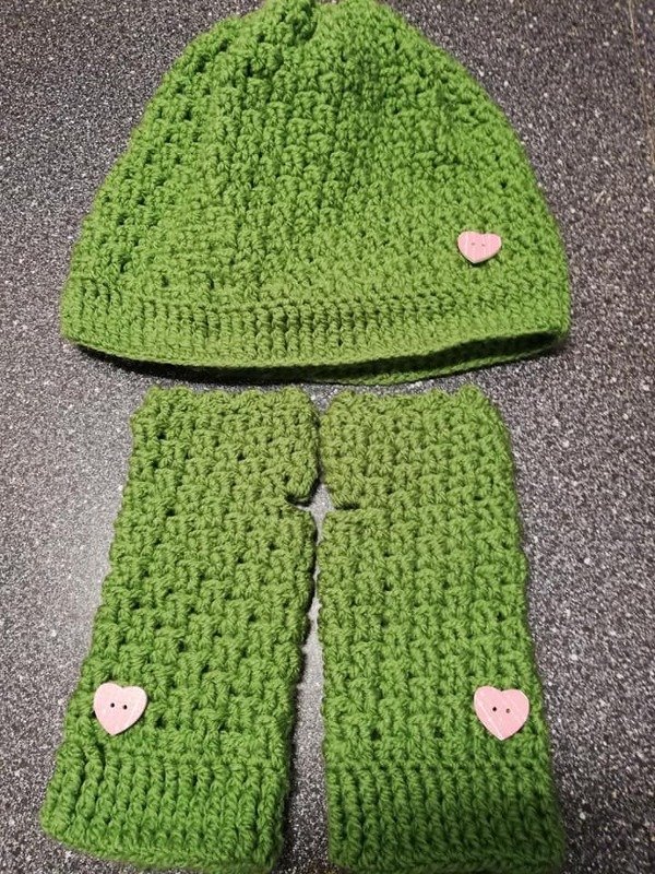 Grünes gehäkeltes Damenset aus Mütze und fingerlosen Stulpen mit rosa Herzknöpfen
