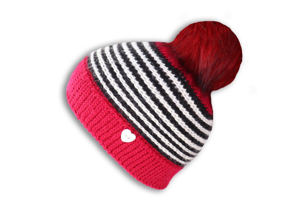 Gestreifte Häkelmütze mit pinkem Saum, rotem Bommel und weißem Herzknopf vor weißem Hintergrund.
