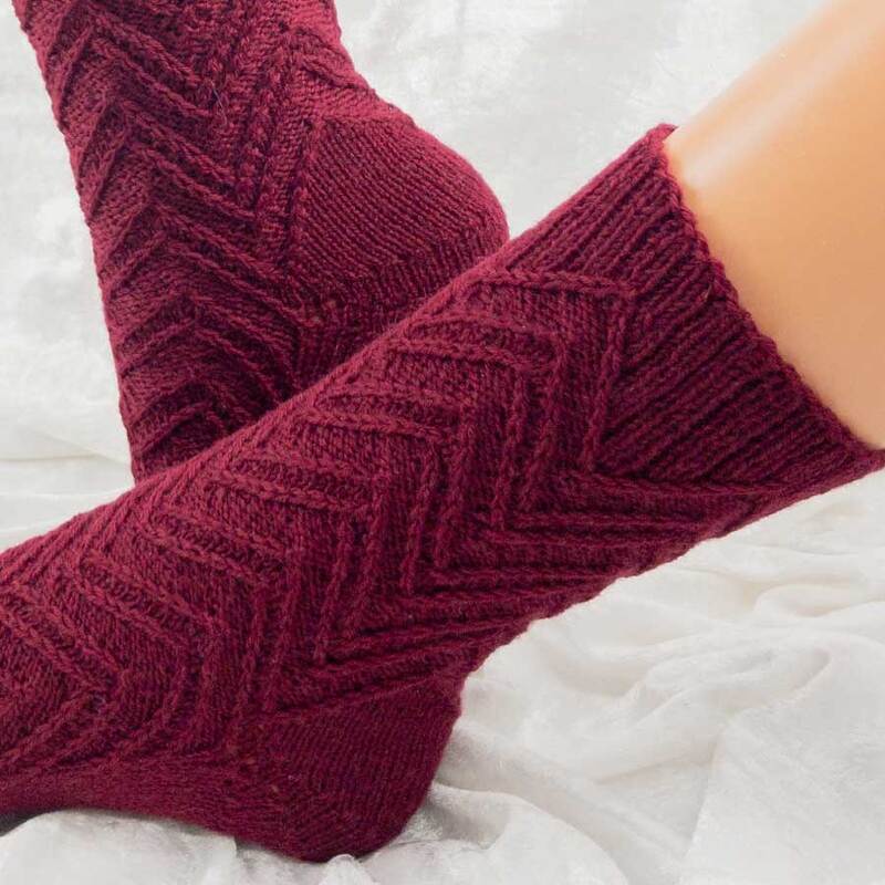 Pair of burgundy chevron-pattern knitted ankle socks on a light fabric background