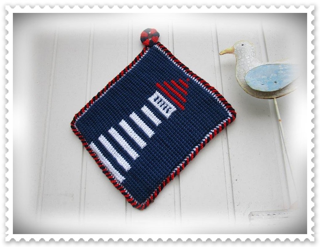 Quadratischer gehäkelter Topflappen in Marineblau mit weißem Leuchtturm, rotem Dach und zweifarbiger Kordelkante