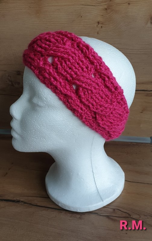 Gehäkeltes pinkes Stirnband mit Zopfmuster auf Modellkopf