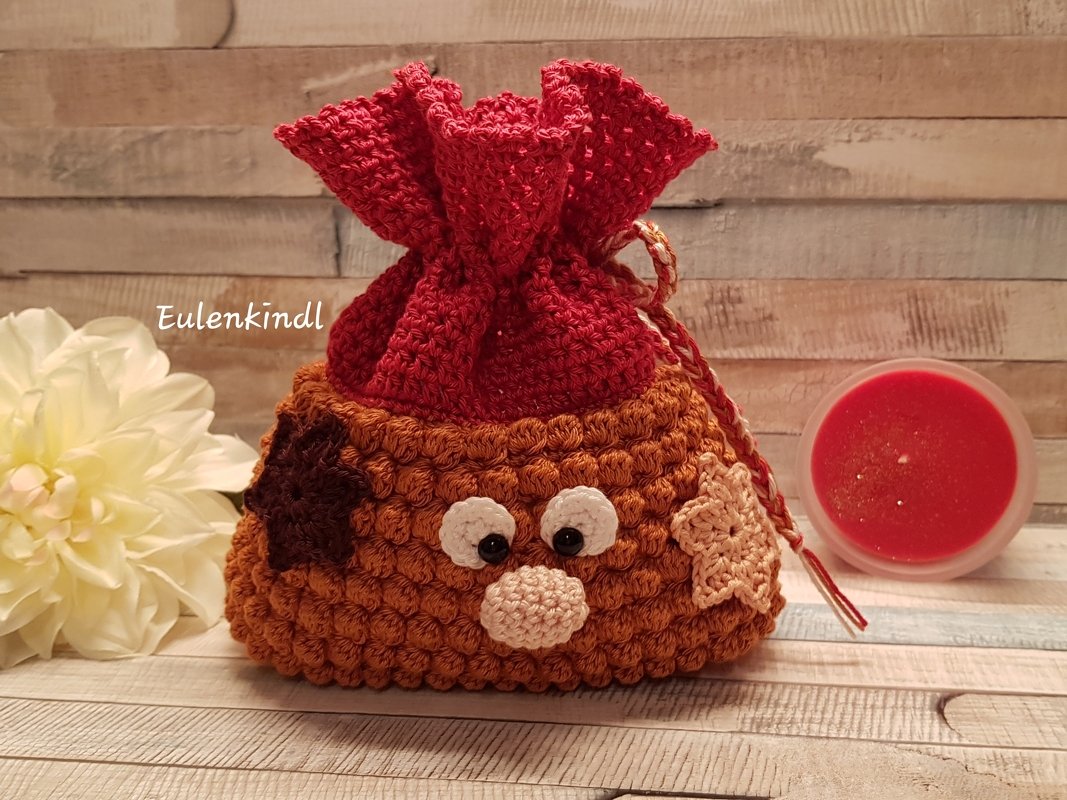 Handgehäkeltes Säckchen in Rot und Braun mit Augen und Nase als dekoratives Geschenk
