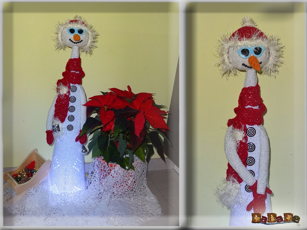 Gehäkelter, beleuchteter Schneemann in Weiß und Rot mit blauen Augen neben Weihnachtsstern (Weihnachtsstern/Poinsettie).