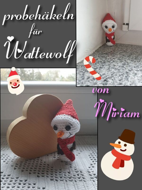 Amigurumi-Schneemann mit roter Mütze und Schal neben einem Holzherz auf einer gehäkelten Decke
