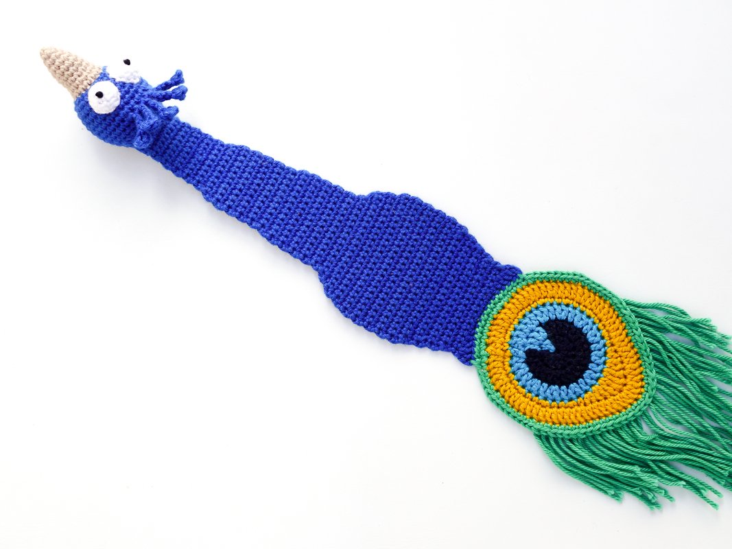 Hand-crocheted blue peacock bookmark with circular eye motif and green fringe