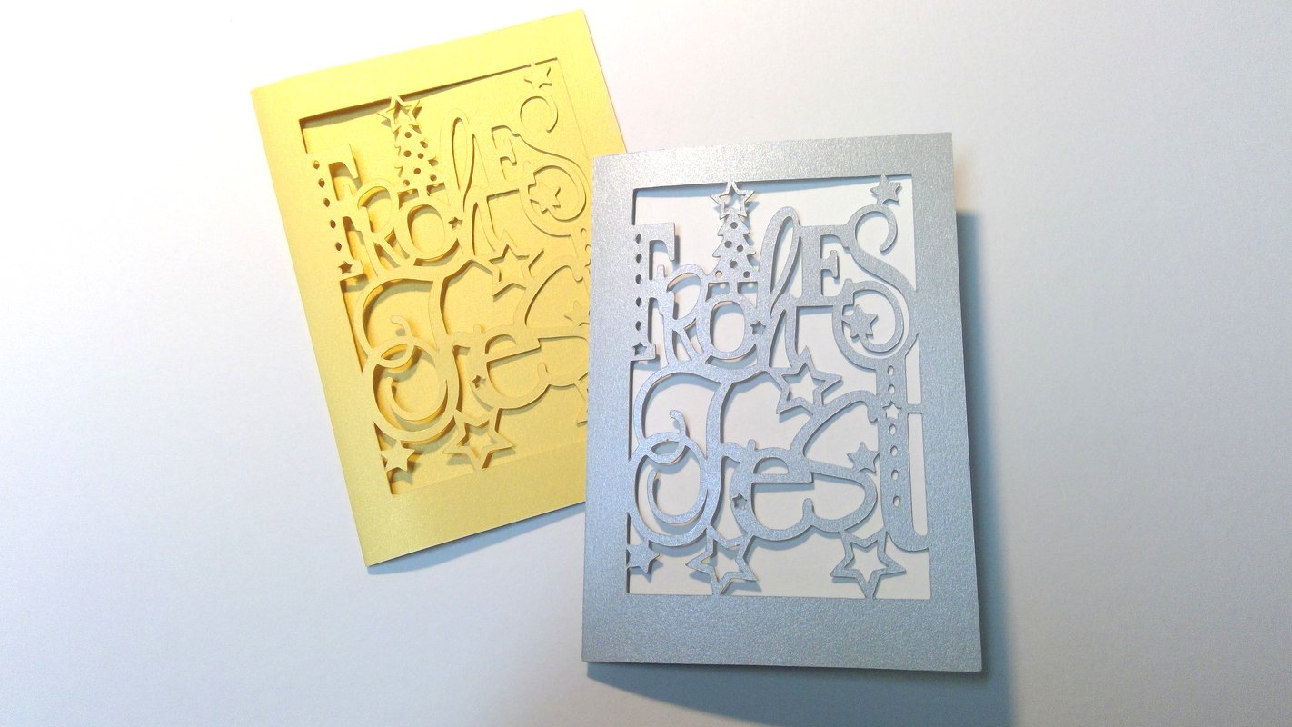 Silberne und gelbe Grußkarte mit ausgeschnittenem Schriftzug 'Frohes Fest', Sternen und Tannenbaum