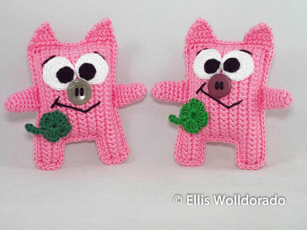 Zwei rosa Amigurumi-Figuren als DIY-Inspiration, mit Knopf-Nasen und gehäkeltem Kleeblatt