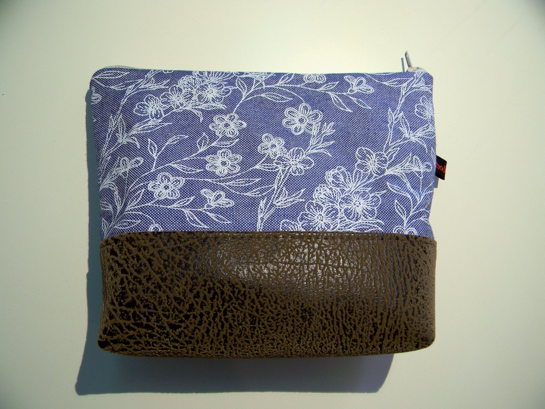 Rechteckige Kosmetiktasche aus blauem Stoff mit weißem Blumenmuster und dunkelbraunem Kunstlederboden