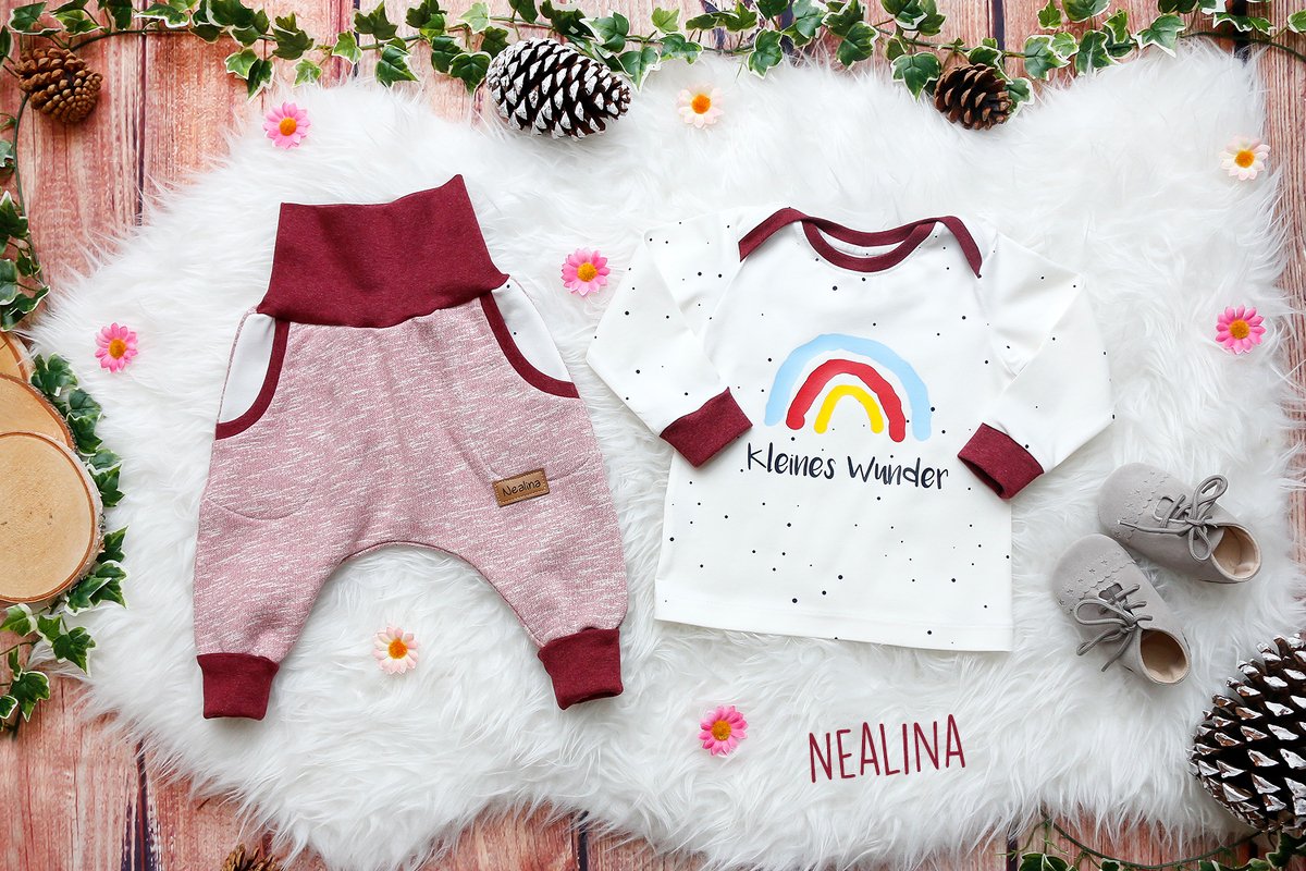 Baby-Set: Regenbogen-Langarmshirt und rosa-beerenfarbene Hose auf flauschigem Teppich