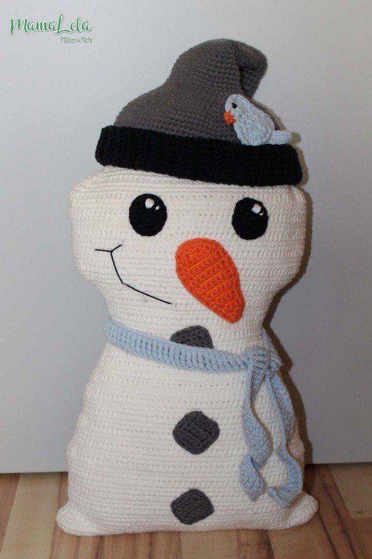 Gehäkeltes Schneemann-Kissen in Weiß mit grauer Mütze, orangefarbener Nase und hellblauem Schal