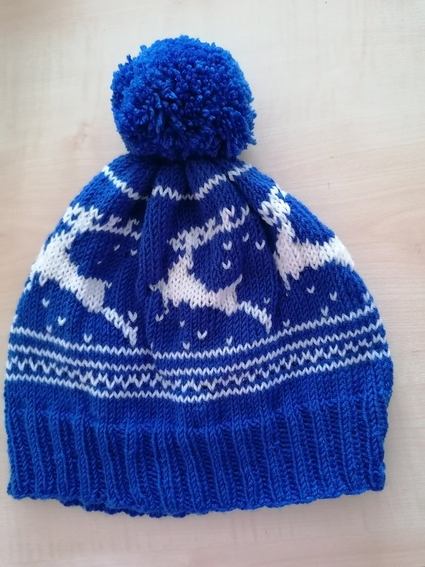 Blaue Strickmütze mit weißem Rentier- und Schneeflockenmuster und blauem Bommel
