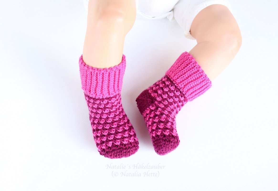 Pink and fuchsia crocheted baby socks with folded ribbed cuffs
