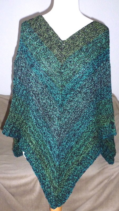 Gestrickter V‑förmiger Poncho in Grün‑ und Petroltönen auf Schaufensterpuppe