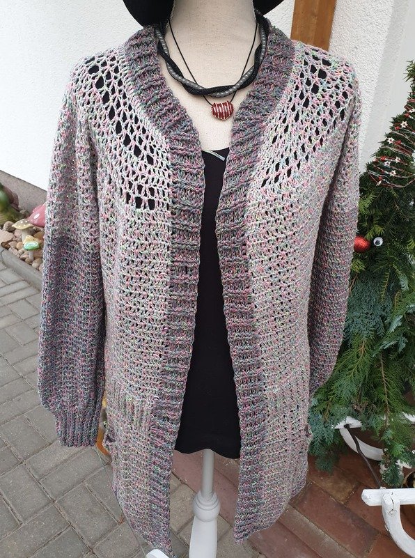 Gehäkelte Damenjacke in Mélange-Farben mit Lochmuster und gerippten Bündchen auf einer Schaufensterpuppe