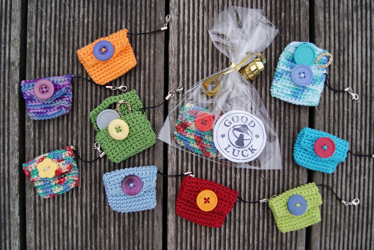 Handgehäkelte bunte Mini-Täschchen mit Knöpfen, einige verpackt mit 'Good Luck'-Anhänger