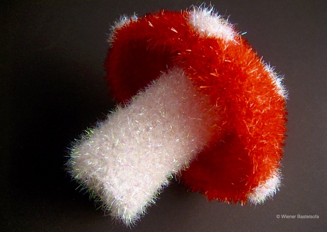 Gehäkelter roter Pilzhut auf weißem gehäkeltem Stiel aus flauschigem Effektgarn