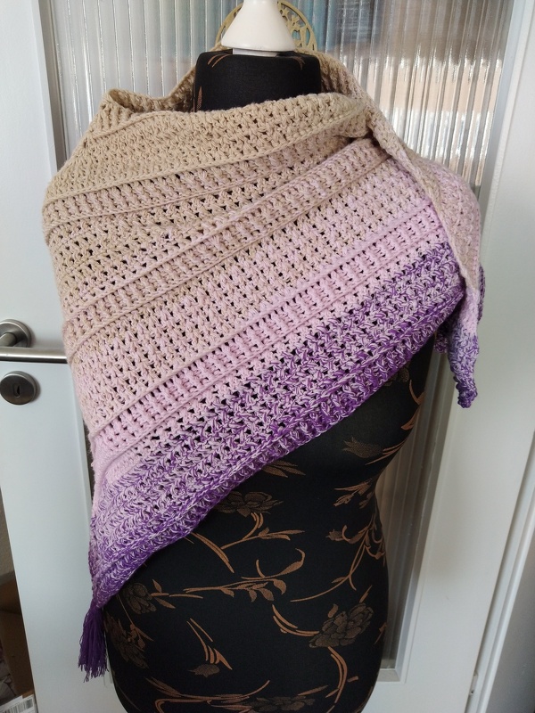 Gehäkeltes Dreieckstuch in Beige, Rosa und Lila auf einer Schneiderpuppe.