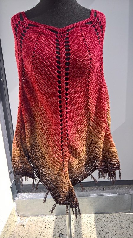 Gehäkelter Poncho in Rot-Orange-Braun mit Fransen auf schwarzer Schneiderpuppe
