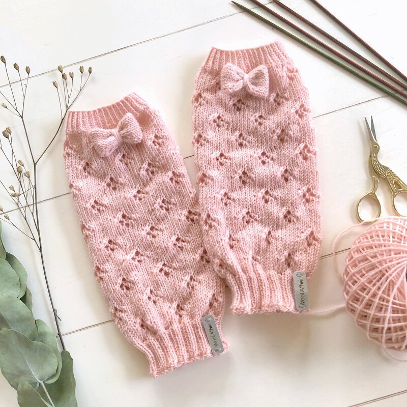 Pair of pastel pink knitted legwarmers with eyelet lace pattern and small bows
