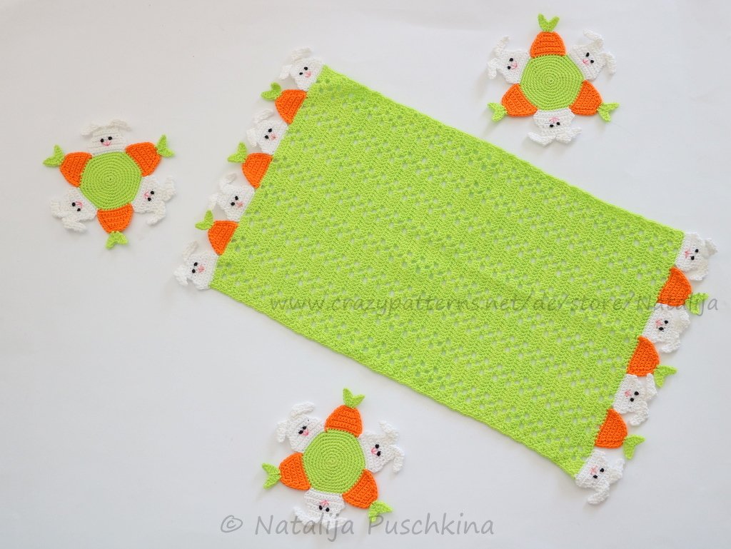 Frühlingsgrüner Häkel-Läufer mit aufgesetzten weißen Hasen und orangen Karotten, ergänzt durch runde Hasen-Untersetzer