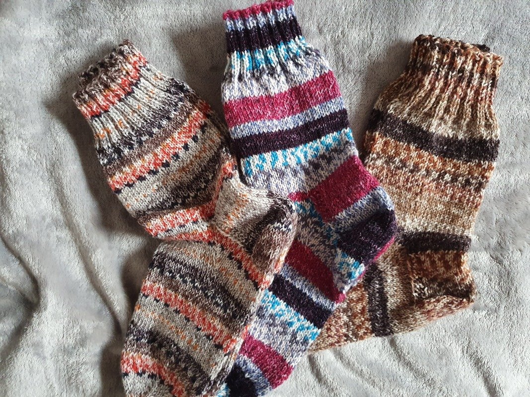 Drei mehrfarbige gestrickte Damensocken mit Streifen auf hellgrauem Stoff