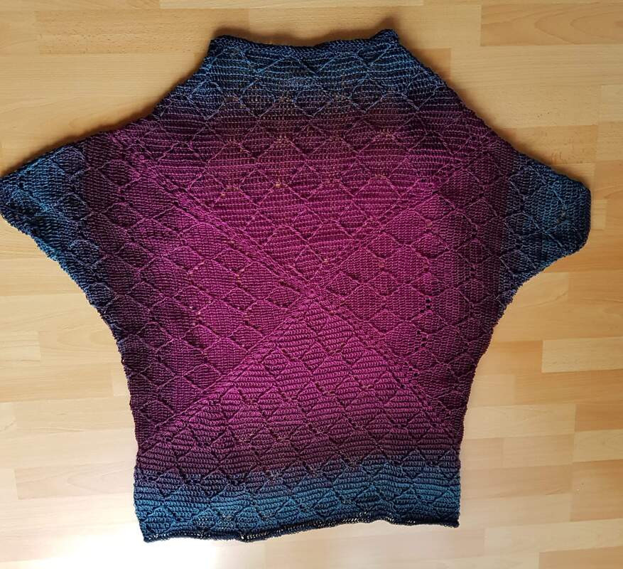 Gehäkelter Seelenwärmer in Blau-Magenta mit Rautenmuster auf Holzboden