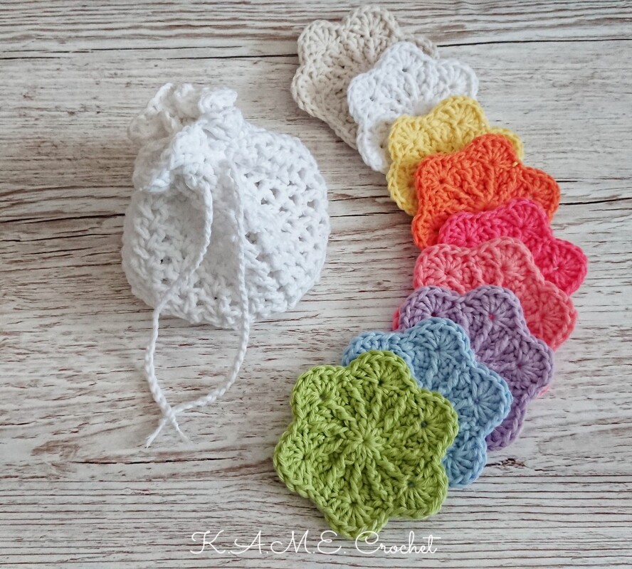 Scalloped crochet motifs in green, blue, purple, pink, orange, yellow and neutral tones next to a small white crocheted drawstring pouch on a wooden background