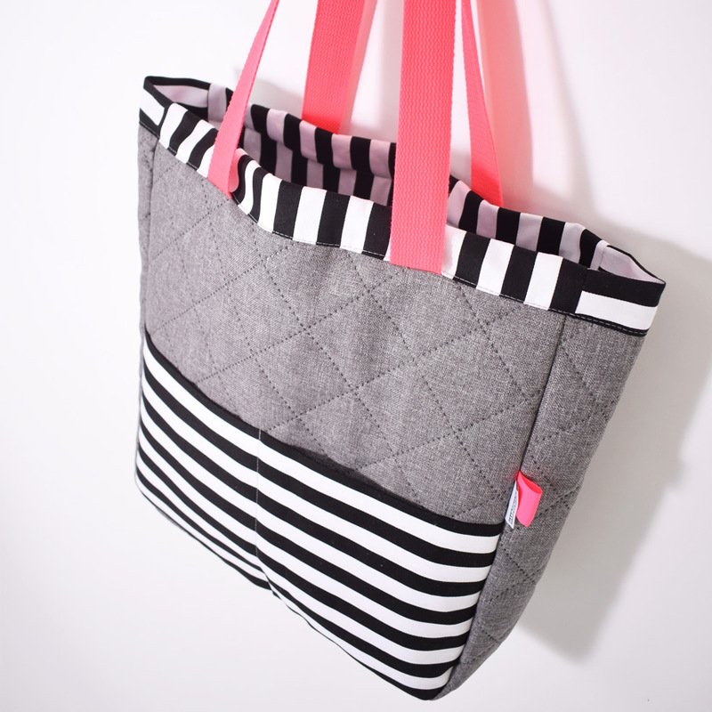 Moderner Shopper aus grauem, gestepptem Stoff mit schwarz-weißen Streifen und rosa Trägern