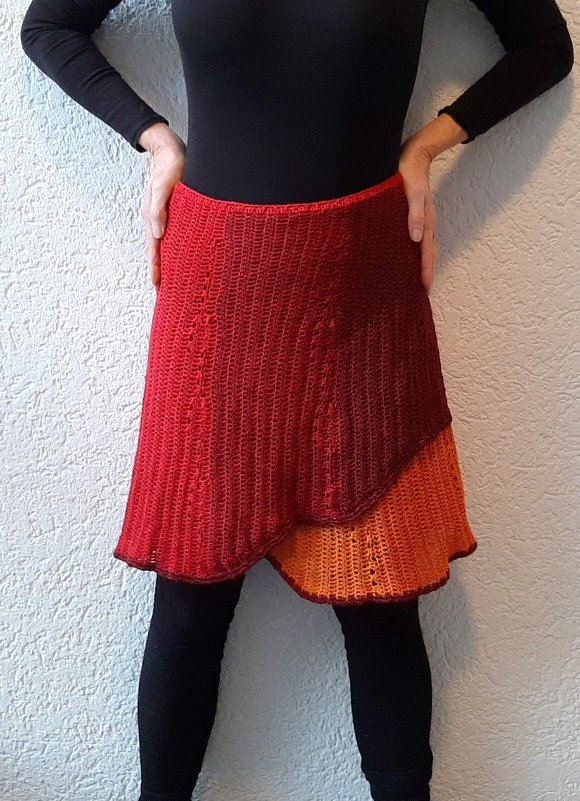 Gehäkelter mehrlagiger Damenrock in Rot‑ und Orangetönen über dunkler Leggings