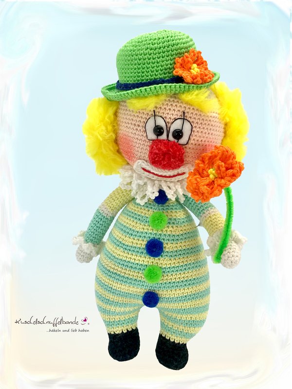Gehäkelter Clown-Amigurumi mit gelbem Haar, roter Nase und orangefarbener Blume