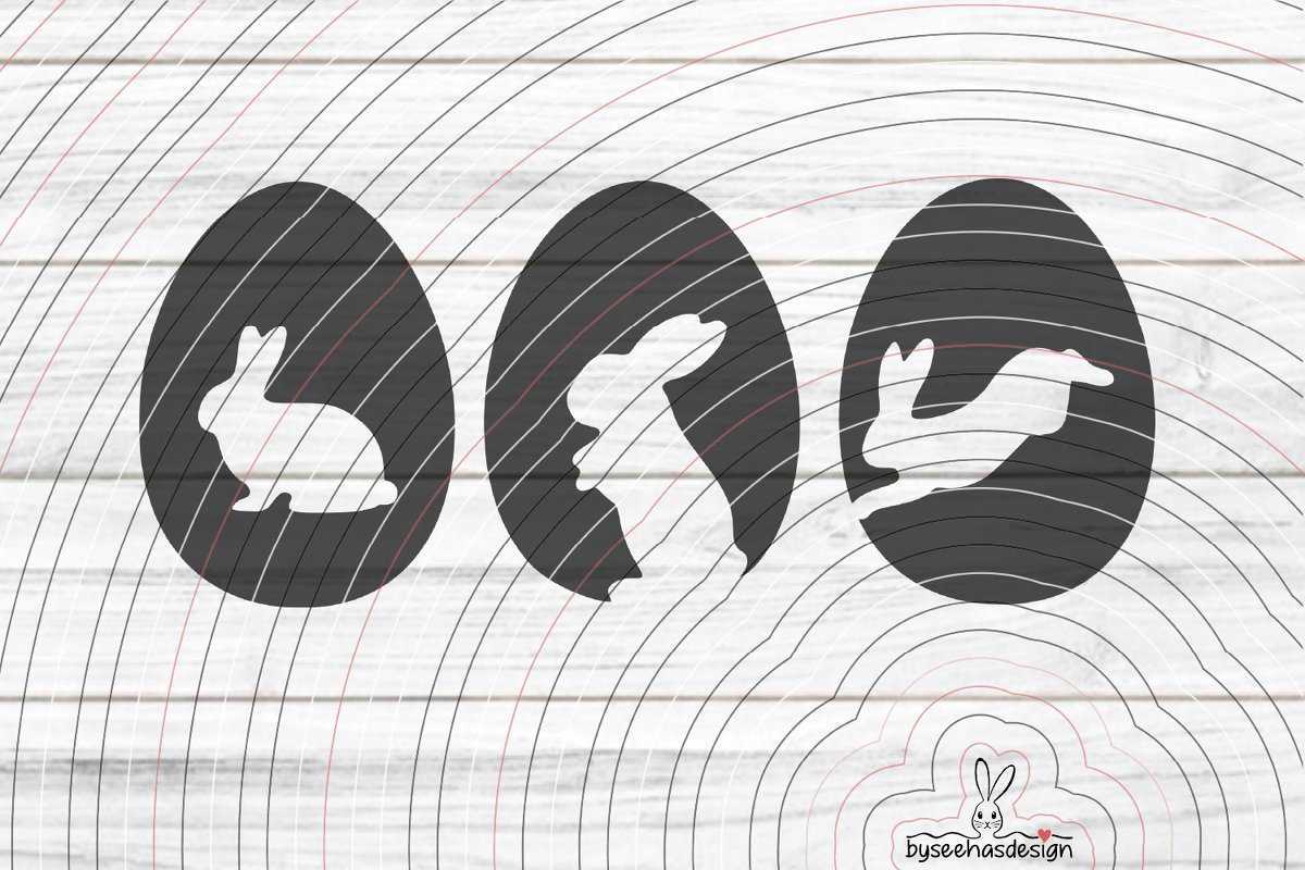 Drei Hasen‑Silhouetten in Ei‑Form auf weißer Holzoberfläche