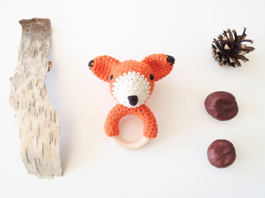 Gehäkelte Fuchsrassel mit Holzring neben Naturdekoration
