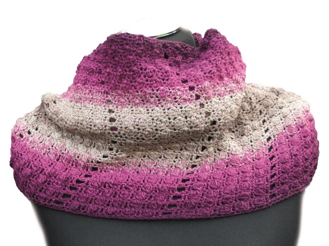 Ombre crochet infinity cowl in magenta to beige with lacy openwork draped on a dress form