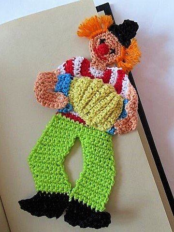 Gehäkeltes Clown-Lesezeichen mit orangefarbenen Haaren, roter Nase, gestreiftem Oberteil und grüner Hose.