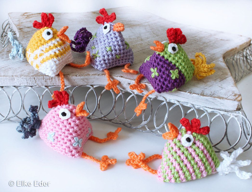 Fünf bunte gehäkelte Amigurumi-Hühner auf Holzbrett