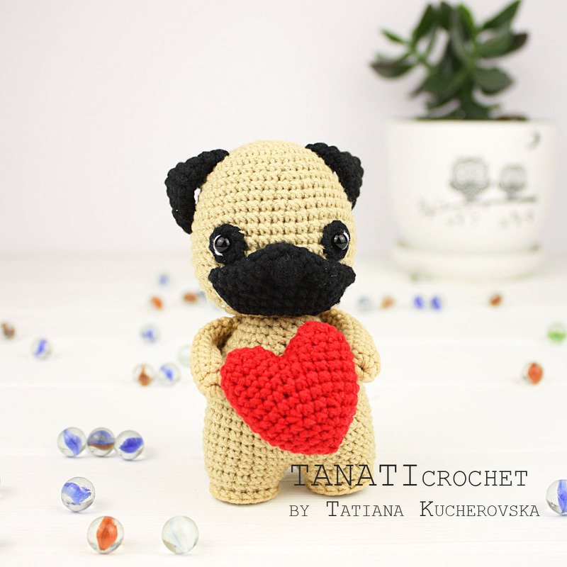 Gehäkelter beiger Amigurumi‑Hund mit schwarzer Schnauze und rotem Herz
