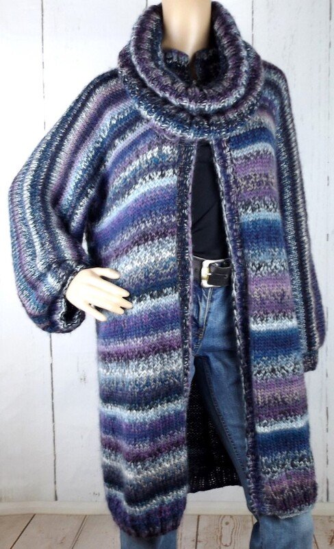 Lange gestreifte Strickjacke in Blau-, Lila- und Grautönen mit Rollkragen an einer Schaufensterpuppe.