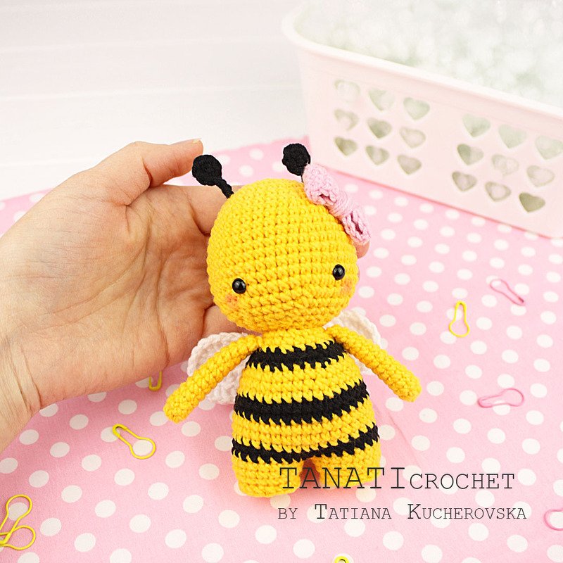 Detailaufnahme einer handgehaltenen Amigurumi-Biene mit gestreiftem Körper, Flügeln und Fühlern