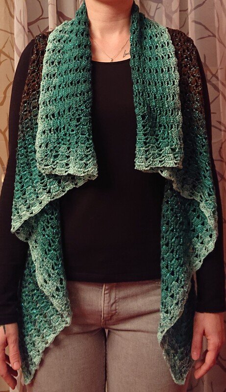 Person trägt lange, grün verlaufende gehäkelte Wasserfallweste mit Ajourmuster