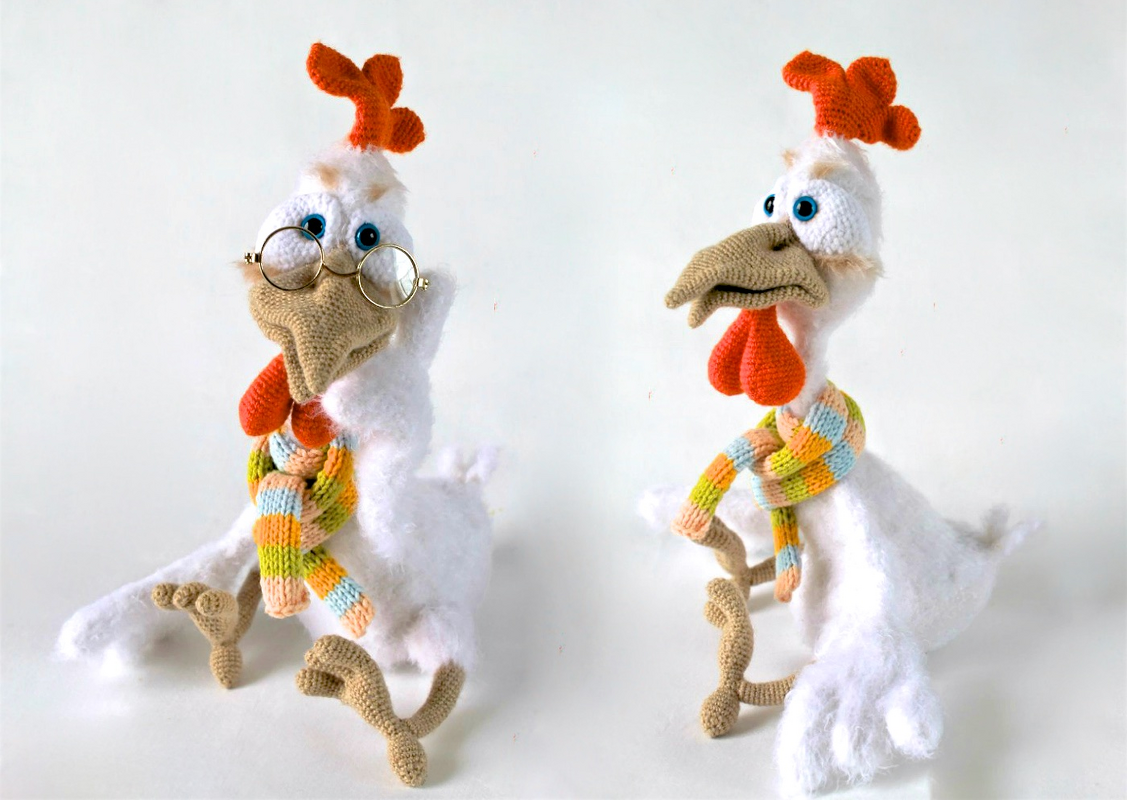 Zwei gehäkelte Amigurumi-Hühner in Pastelltönen mit orangefarbenem Kamm und buntem Schal; links mit runder Brille.