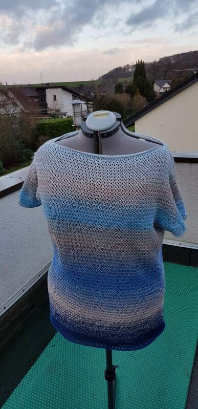 Rückansicht gehäkeltes Kurzarmshirt in blau-beige Farbverlauf auf Schneiderpuppe auf Balkon