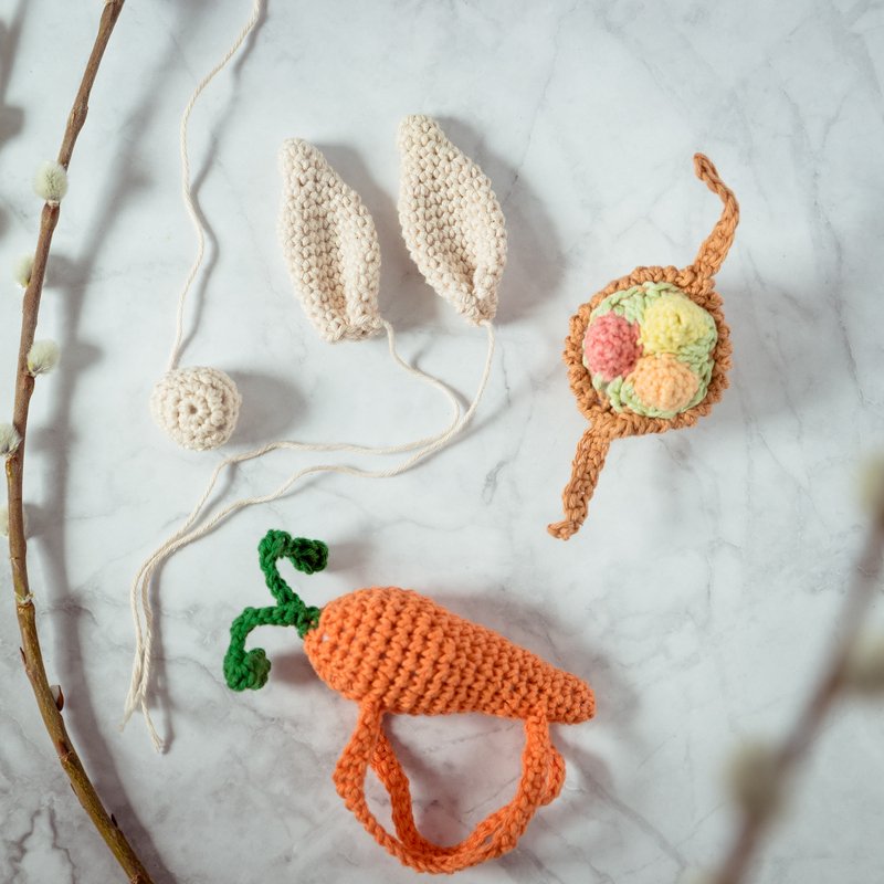 Schnell gehäkelte Oster-Accessoires: Hasenohren, Karottenform, Nest mit bunten Pompoms und kleine Kugel