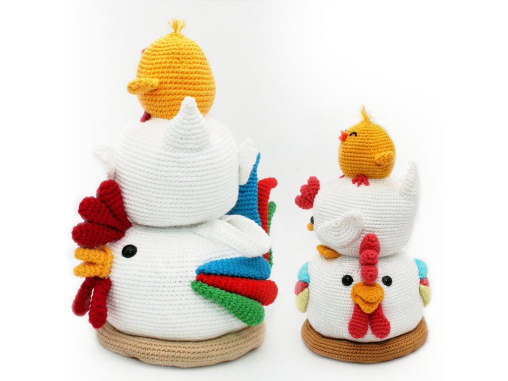 Zwei gehäkelte Huhn-Türstopper mit bunten Flügeln und jeweils kleinem gelbem Küken obenauf