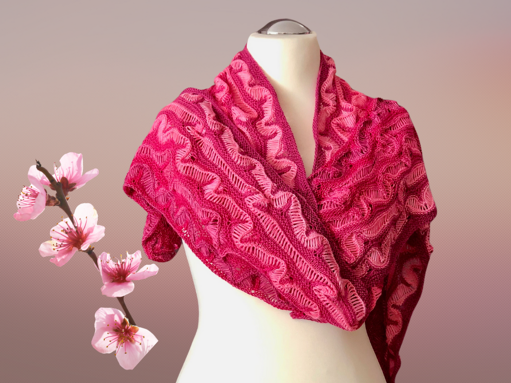 Fein gestricktes Dreieckstuch in Rosa-Magenta mit Ajour- und Wellenmuster auf einer Schaufensterpuppe