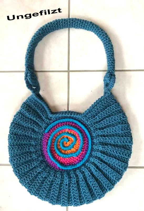 Ungefilzte blaue gehäkelte Henkeltasche mit mehrfarbiger Spirale auf hellem Fliesenboden
