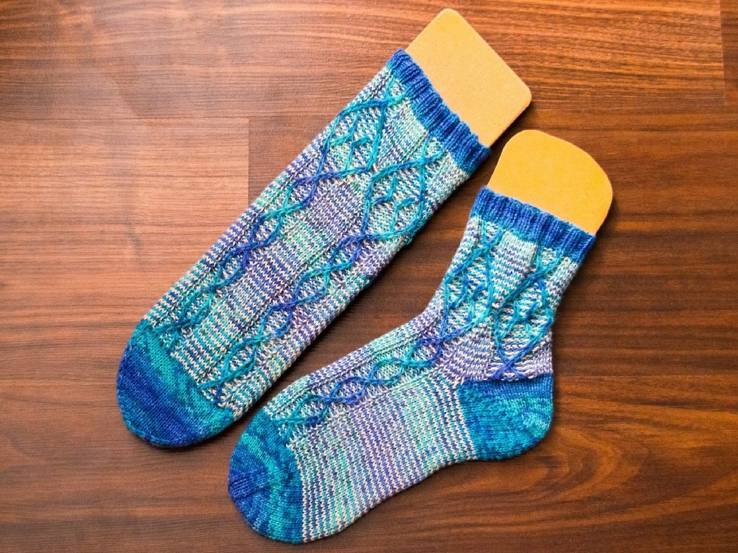 Handgestrickte Socken in Blau- und Türkistönen mit Zopfmuster auf Sockenbrettern