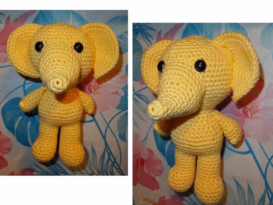 Gelber gehäkelter Amigurumi-Elefant, stehend, große Ohren, schwarze Augen, floraler Hintergrund